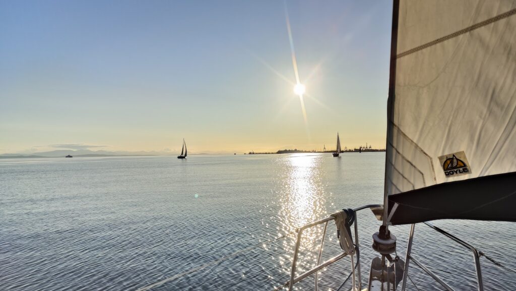 Sailboat silhouetted against a sunset, inviting you to join LMYC and live your yachting